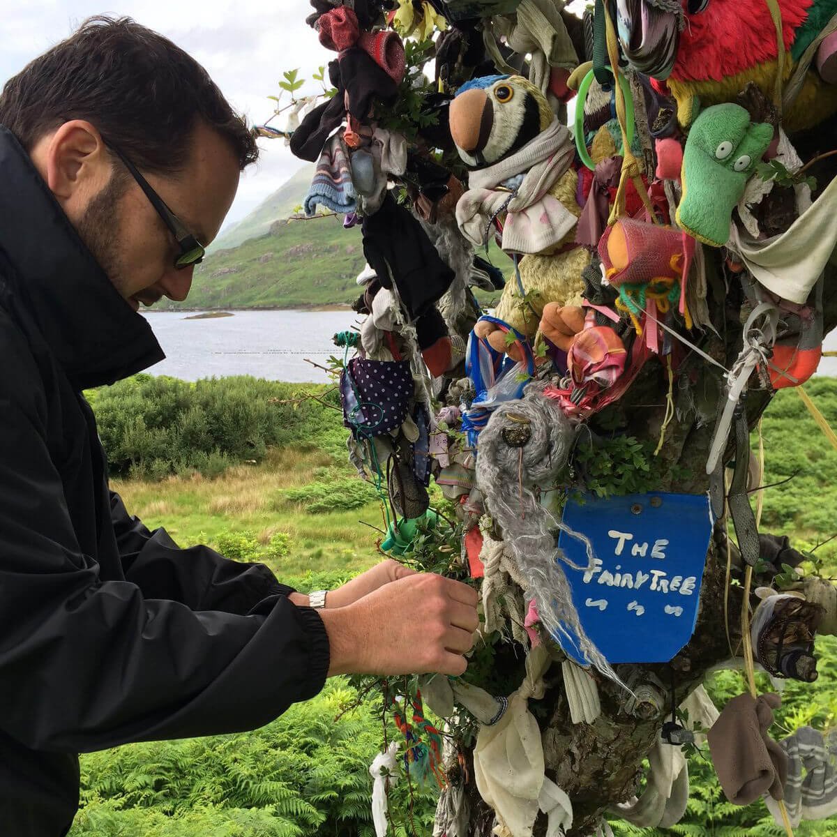 Fastening a charm to a fairy rag tree in Ireland