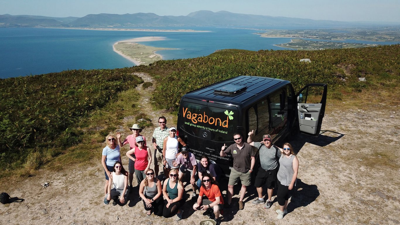 Vagabond tour group posing beside tour vehicle at scenic spot on Ring of Kerry in Ireland