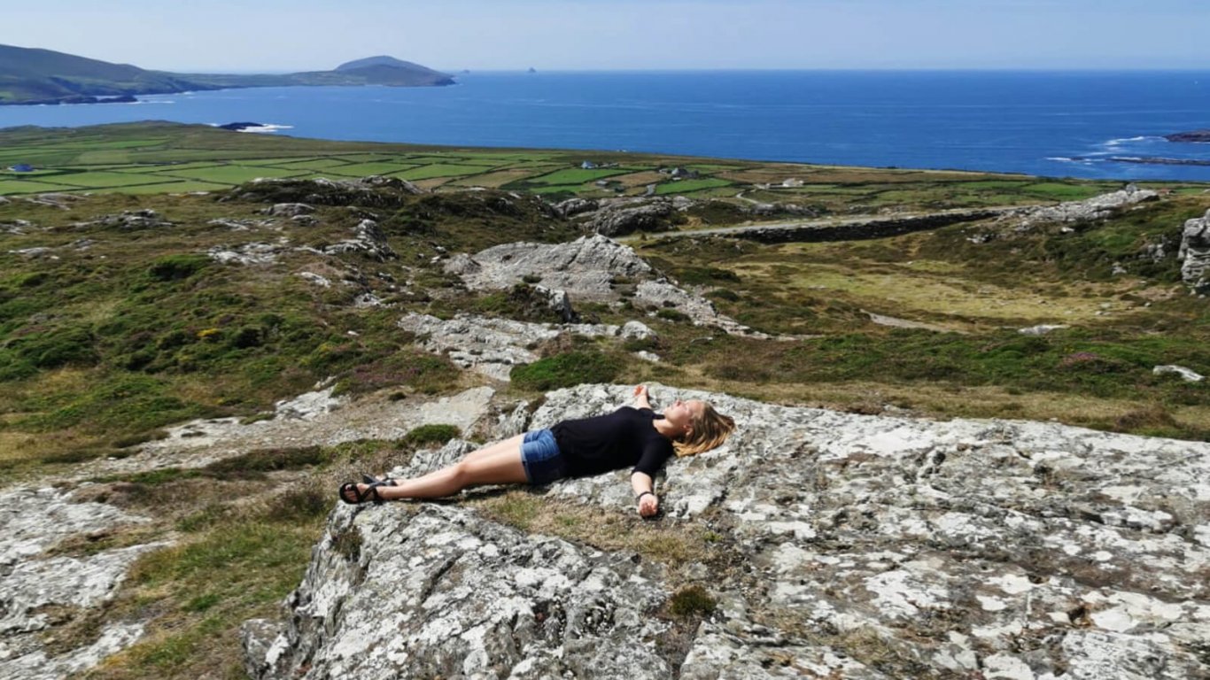 Female Vagabond tour guest lying in a scenic landscape in Ireland looking serene