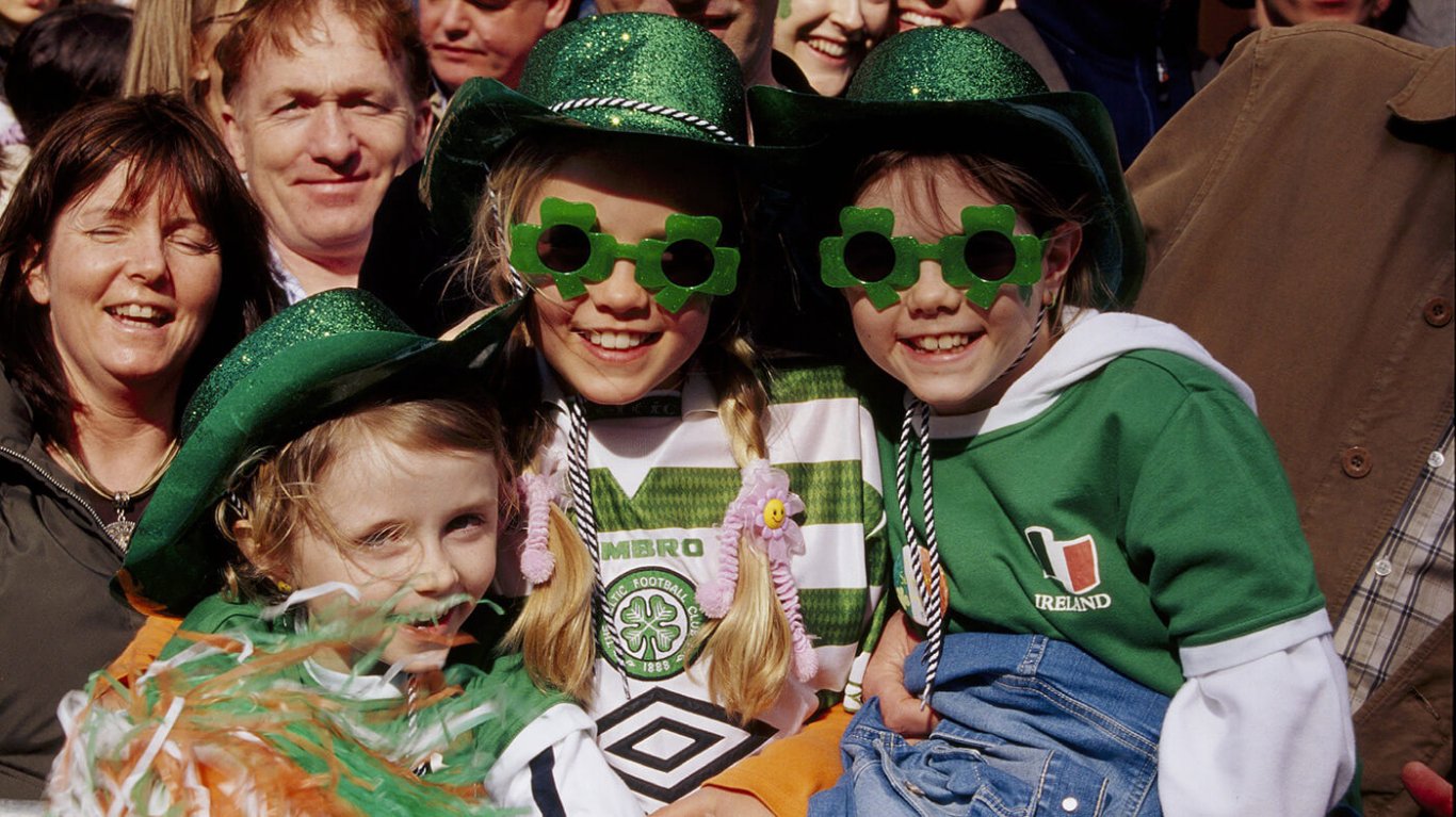 Three kids dressed up in green jerseys and clothes and glasses at a st patricks day parade