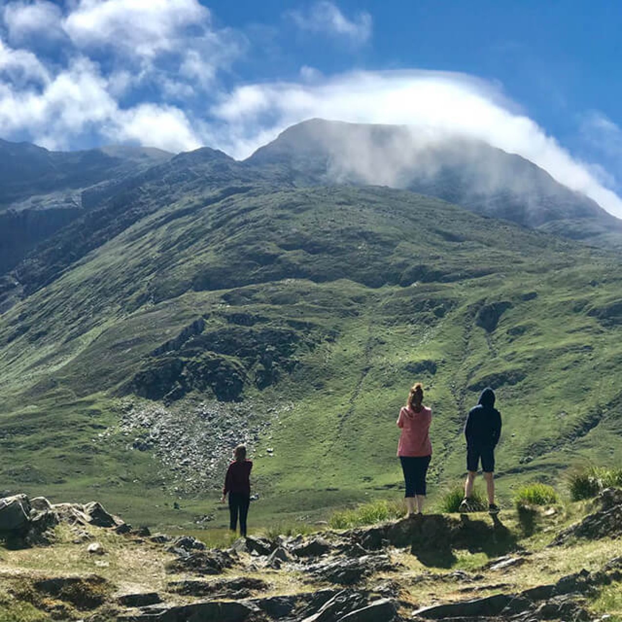 Three guests standing in front of Mweelrea mountain taking picture