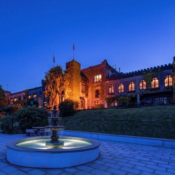 The exterior view of the stunning Abbeyglen Castle Hotel at dusk with water fountain The exterior view of the stunning Abbeyglen Castle Hotel at dusk with water fountain