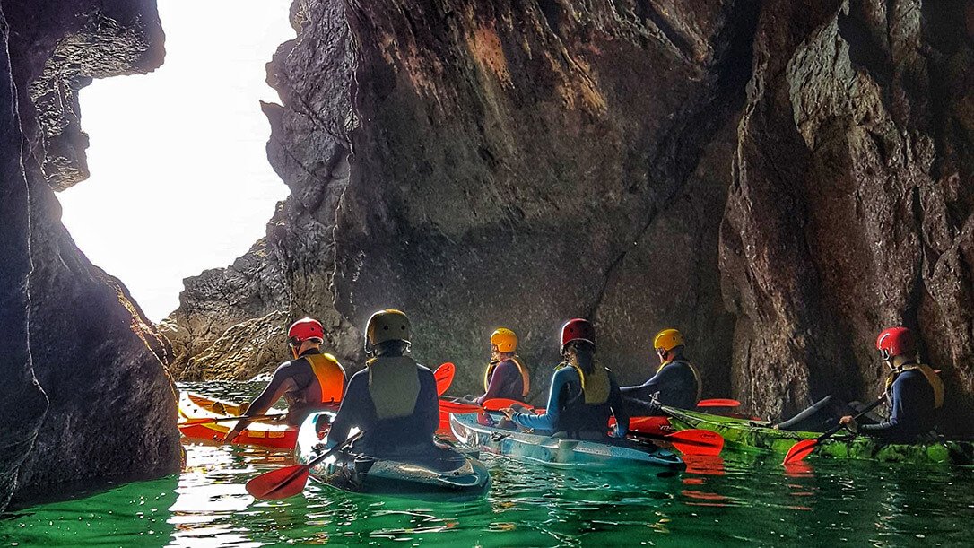 a group of kayakers exploring a sea cave