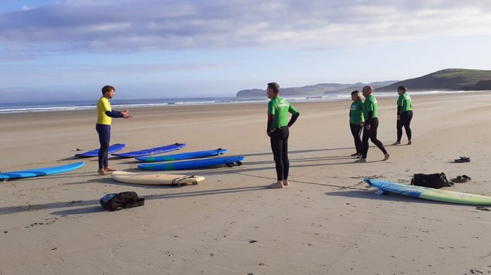 Four guests having a surf lesson on the beach 