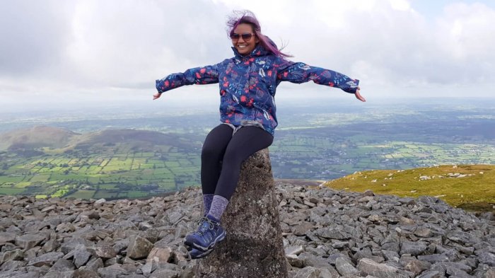Female tour guest sitting on top of the summit of Slieve Gullion mountain summit in Ireland