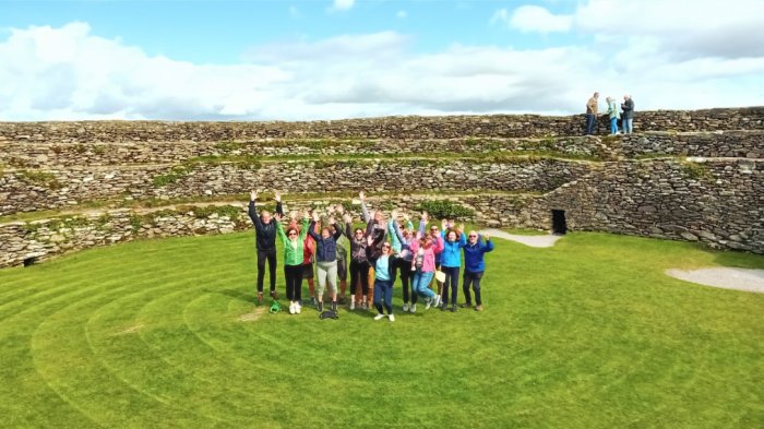 Experience stunning views by climbing the stone ringfort at Grianán of Aileach. A tour group in the centre of an grianan of aileach