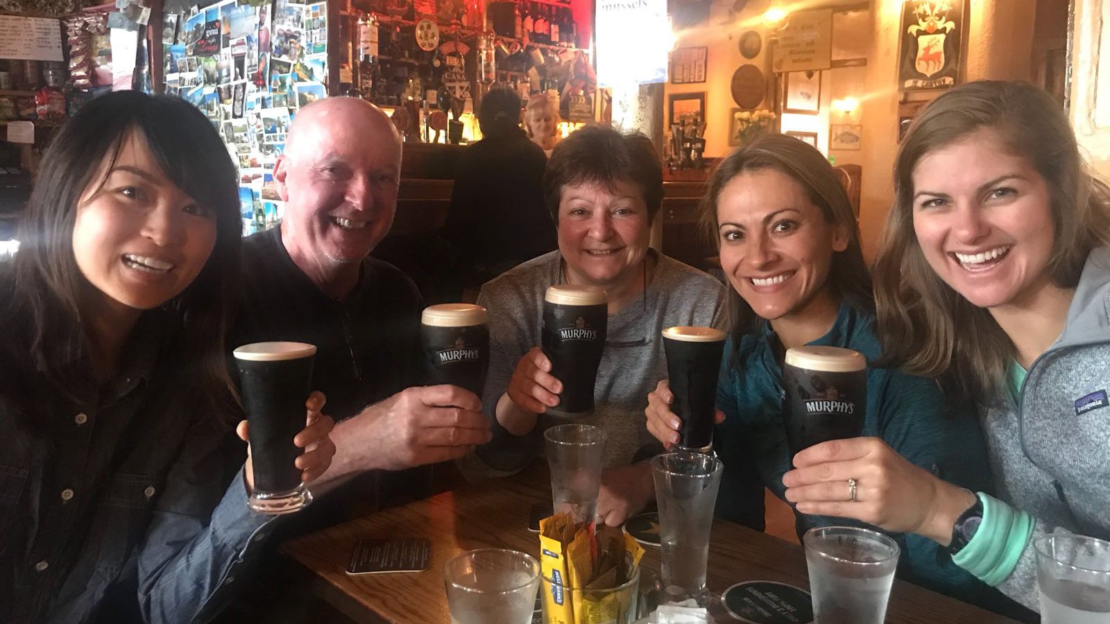 Group toasting the camera with glasses of beer in an Irish pub