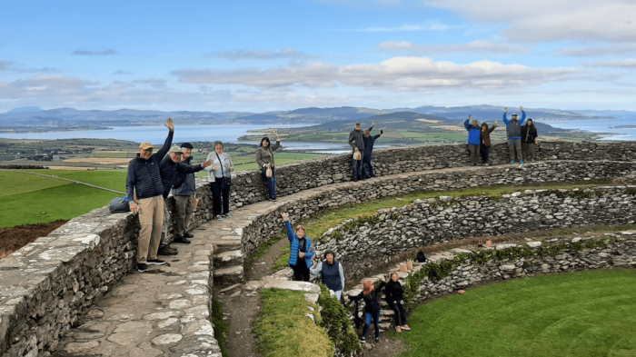 Climb the ancient walls of Grianan Of Aileach A group pf guests standing on grianan of aileach waving