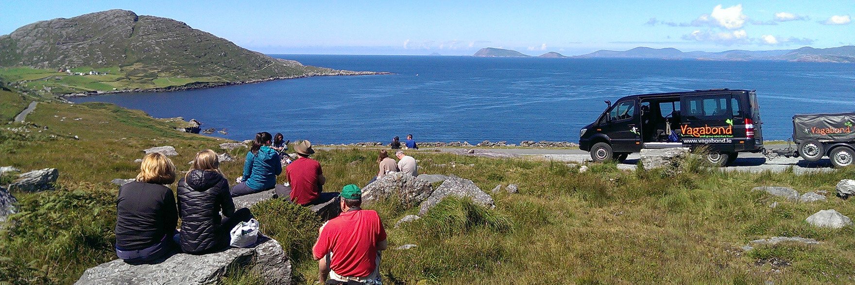 A Vagabond Tour Group picnicking in a scenic location in Ireland with a 4x4 VagaTron tour vehicle parked nearby