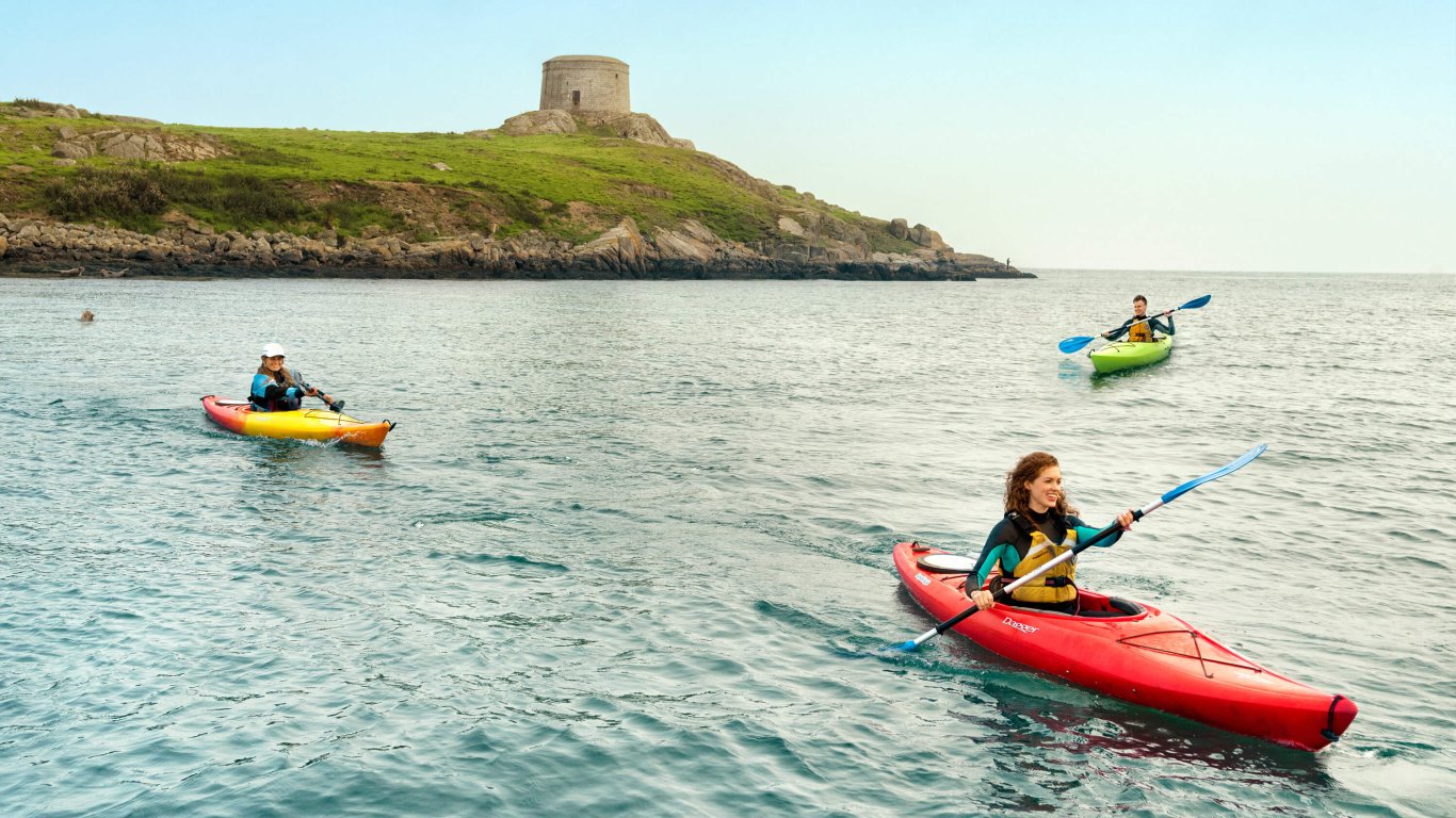 Three young people kayaking around Dalkey Island Three young people kayaking int the sea around Dalkey Island