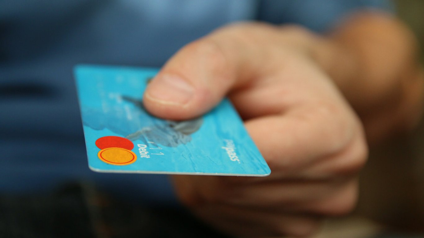 A man holding a credit card in his hand A man's hand holding out a credit card